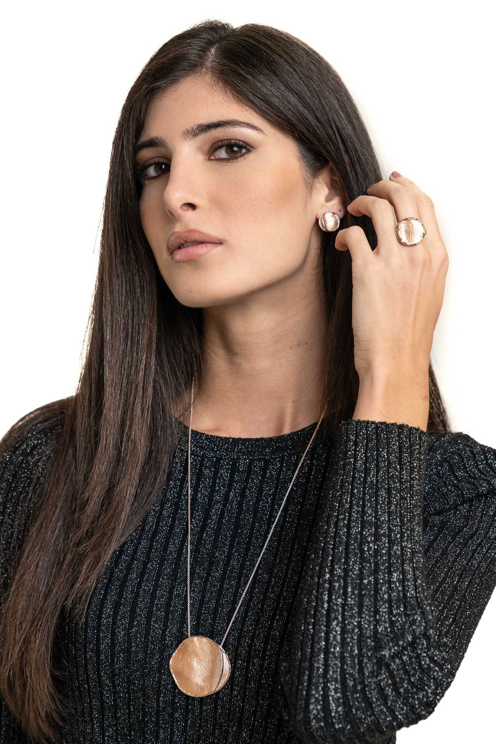 Collana lunga regolabile con pendente dipinto a mano.  Lunghezza collana: 85 cm (regolabile) Diametro pendente: 4,5 cm  Materiale: zama con bagno in oro rosa  Tonalità smalti: blu o beige. Collezione Minerva di KLK. Foto con modella.