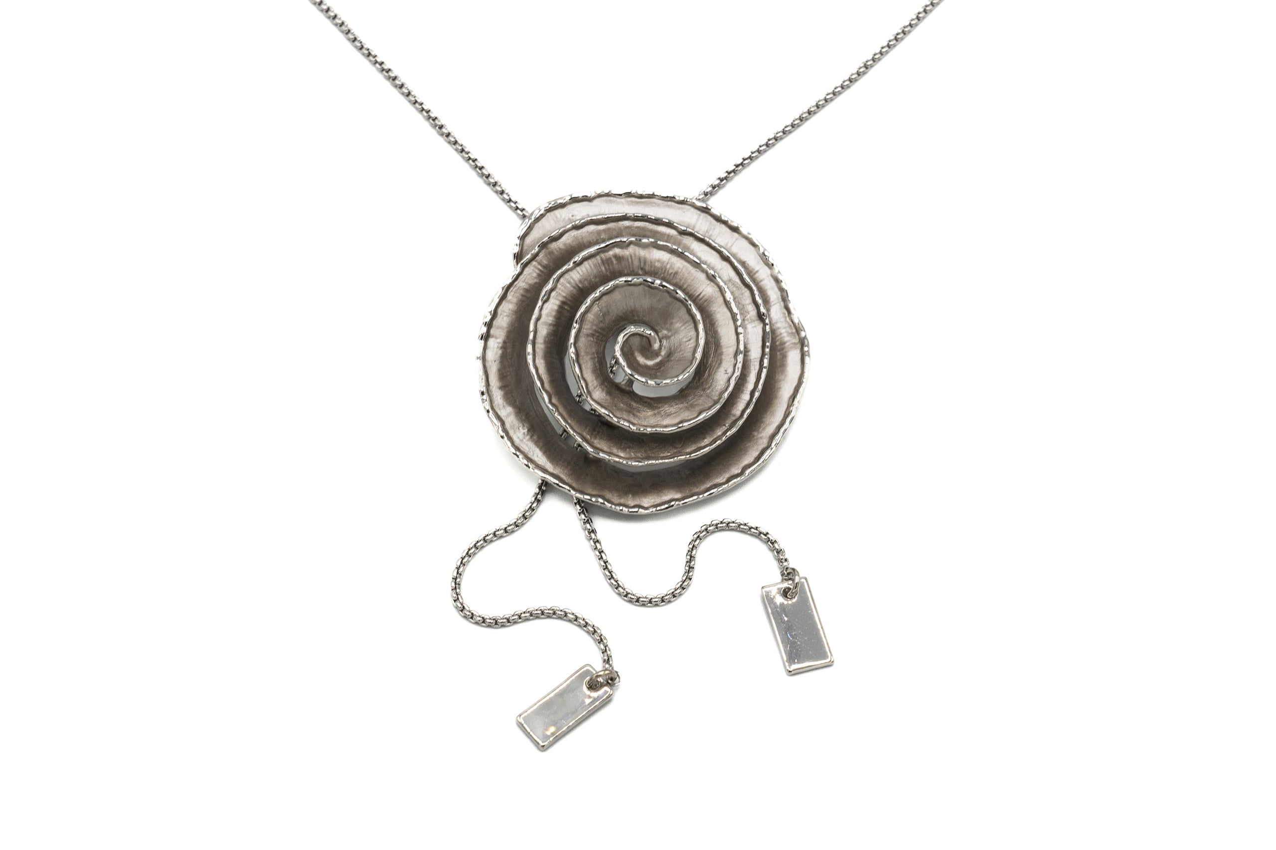 Collana lunga a cravatta con altezza del pendente regolabile. Pendente dipinto a mano.  Lunghezza: 95 cm (altezza pendente regolabile)  Diametro pendente: 4,5 cm  Materiale: zama con finitura galvanica in oro rosé o rodio  Tonalità smalti: verde o grigio