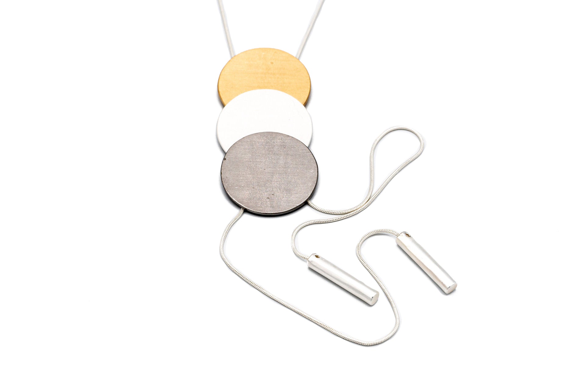 Collana lunga regolabile con tre tondi in tre bagni diversi. Lunghezza: 84 cm (regolabile)  Altezza tre tondi: 7,2 cm  Materiale: zamak con bagno in argento, rodio e oro. Foto frontale. Collezione Venere di KLK.